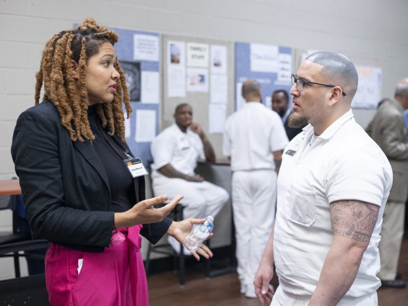 PEP volunteer speaks one-on-one with a program participant in white uniform during a mentoring session inside prison.