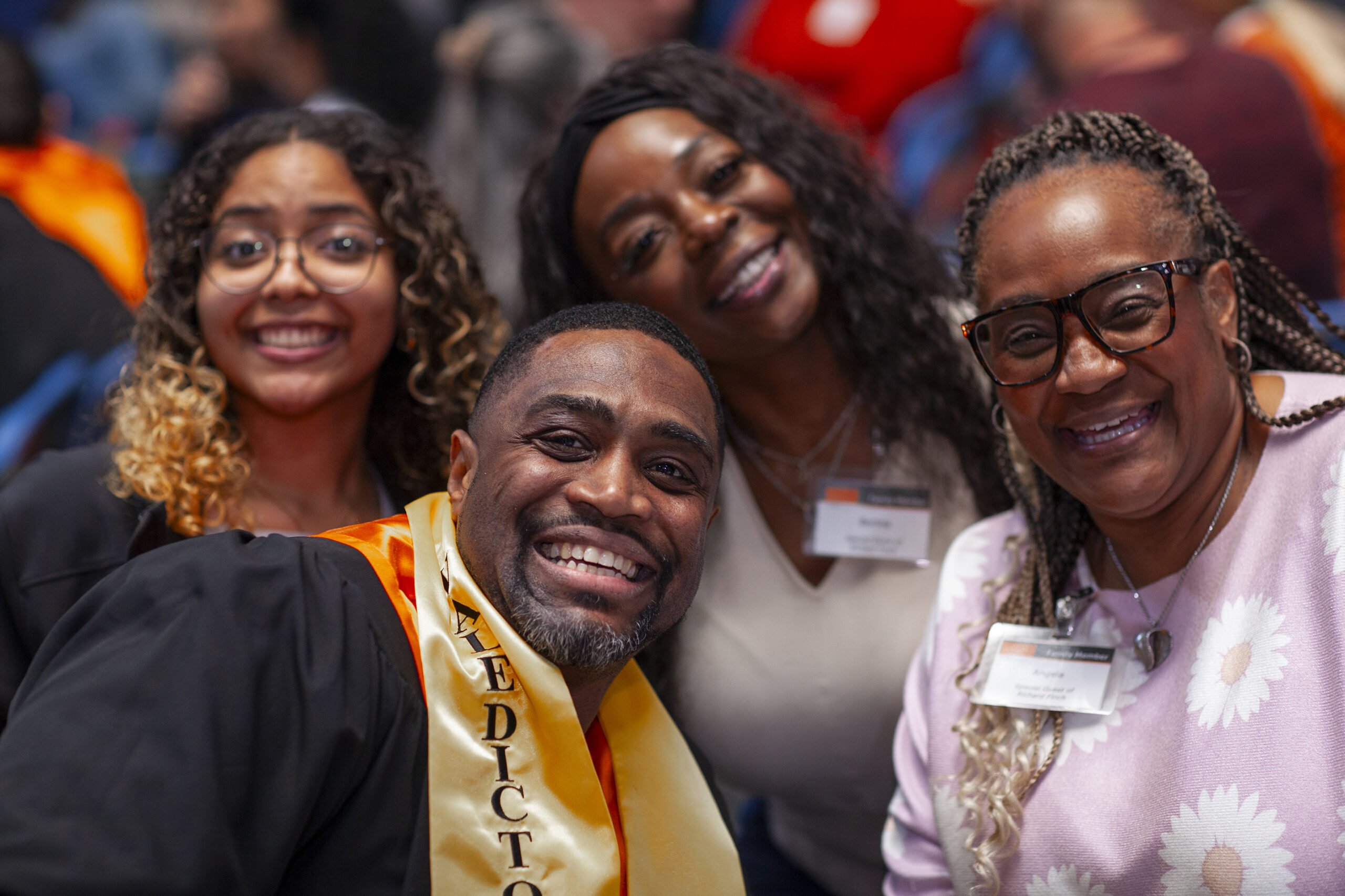 PEP graduate wearing valedictorian sash celebrating with family and supporters at ceremony